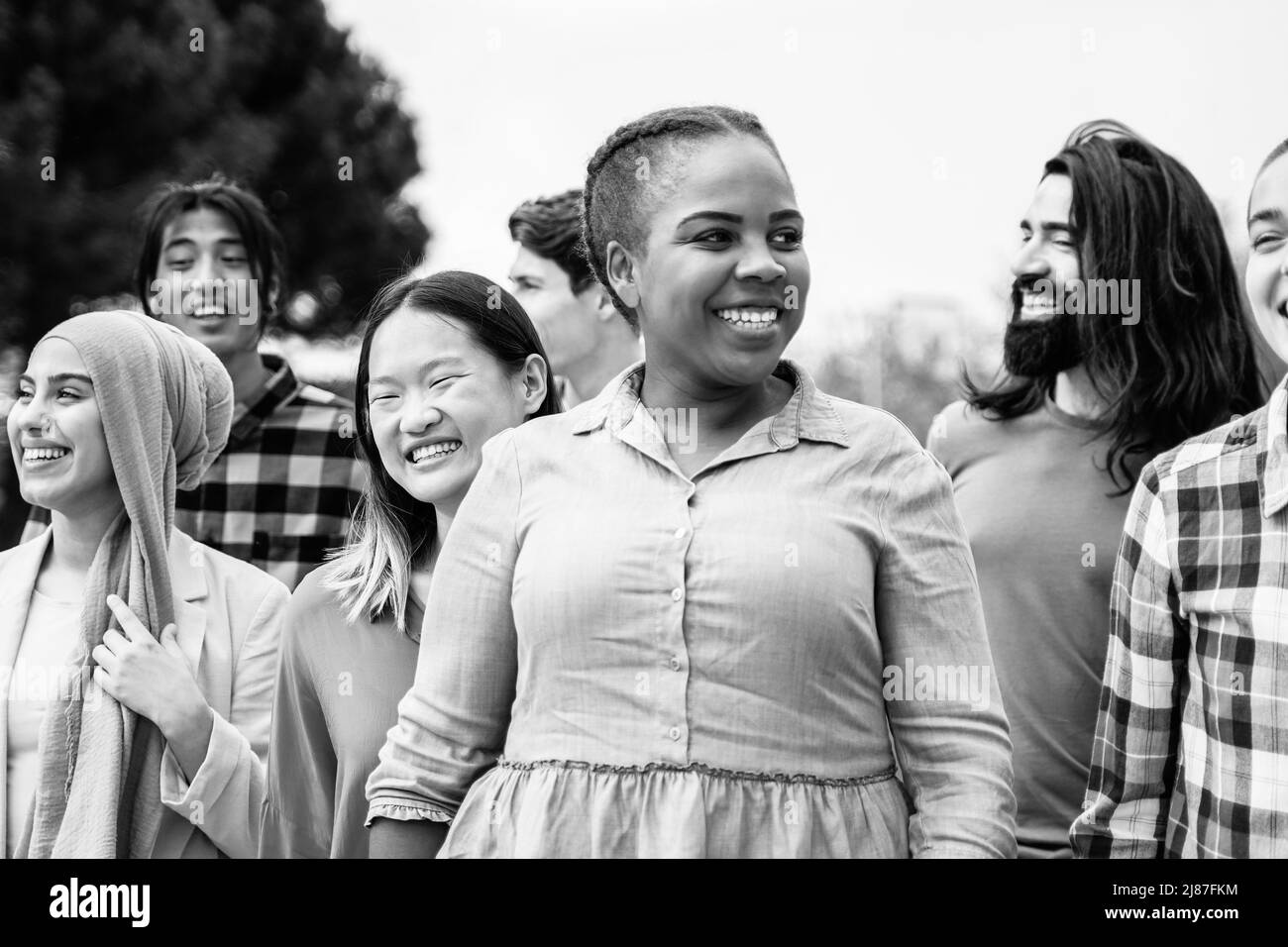 Gente joven multiétnica que se divierte caminando juntos al aire libre - Enfoque en la cara femenina asiática - Edición en blanco y negro Foto de stock