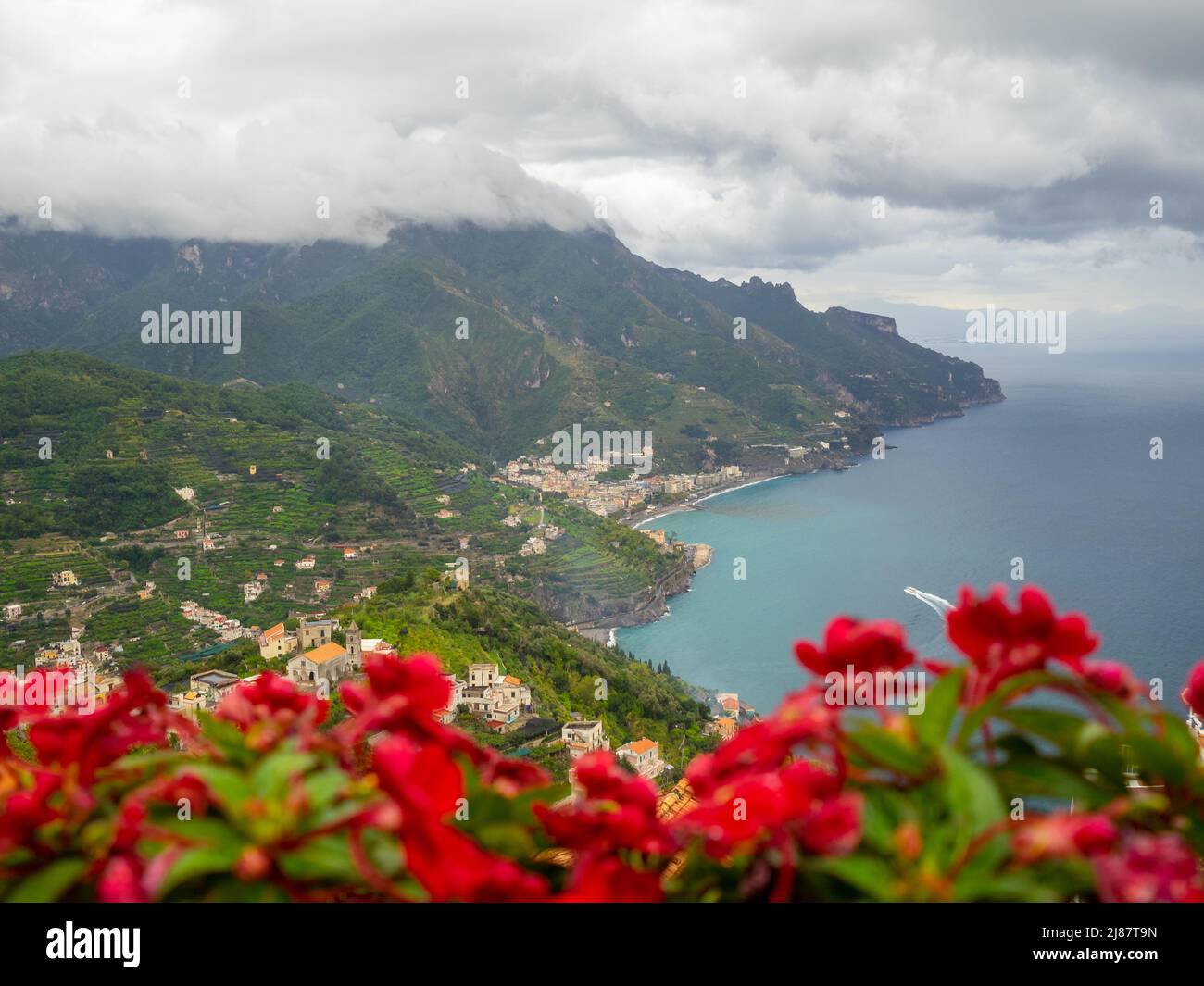 Flores rojas en los jardines de Villa Rufolo con la costa de Amalfi al fondo Foto de stock
