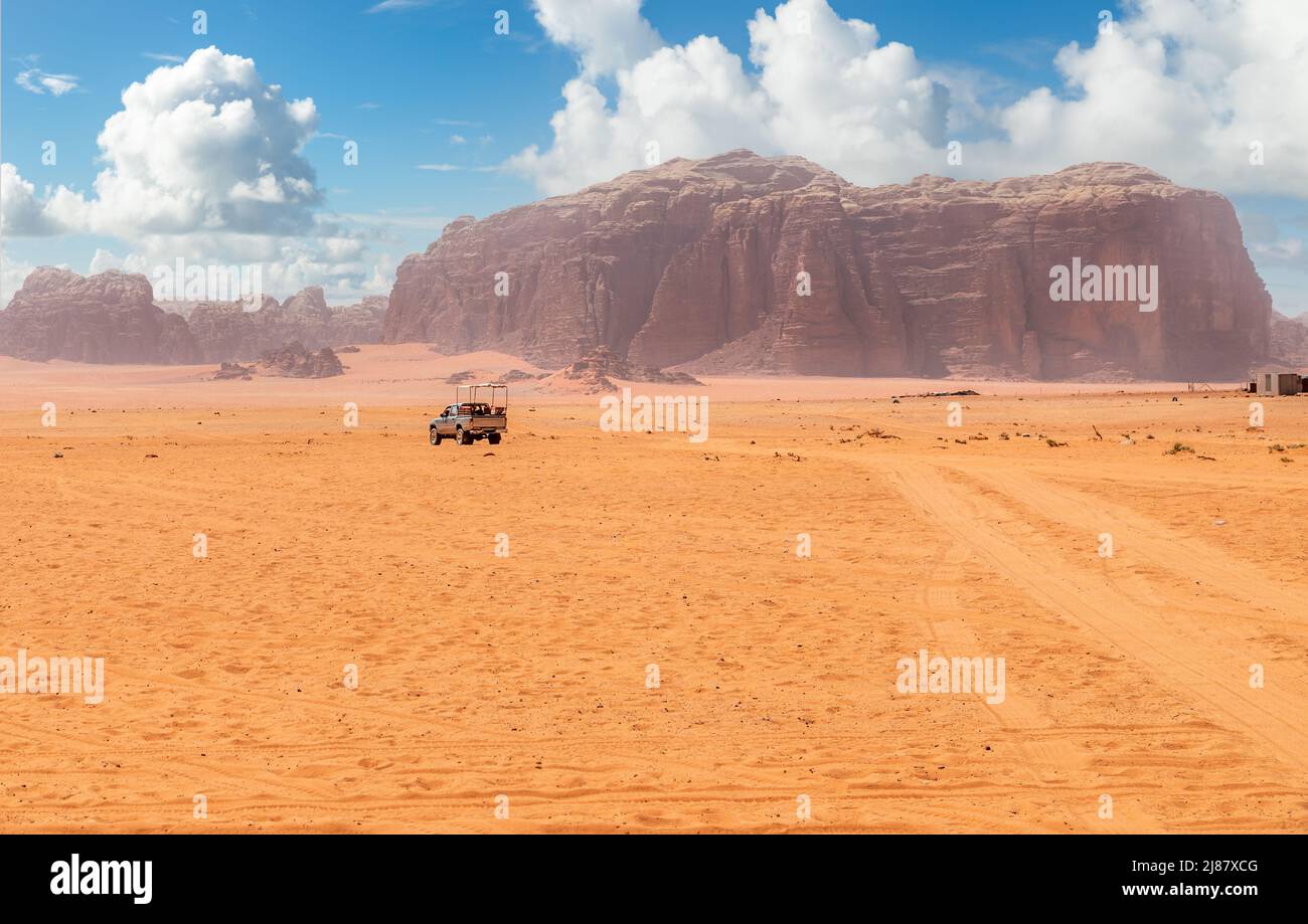 Arenas naranjas y acantilados del desierto de Wadi Rum con coche turístico en el fondo, Jordania Foto de stock