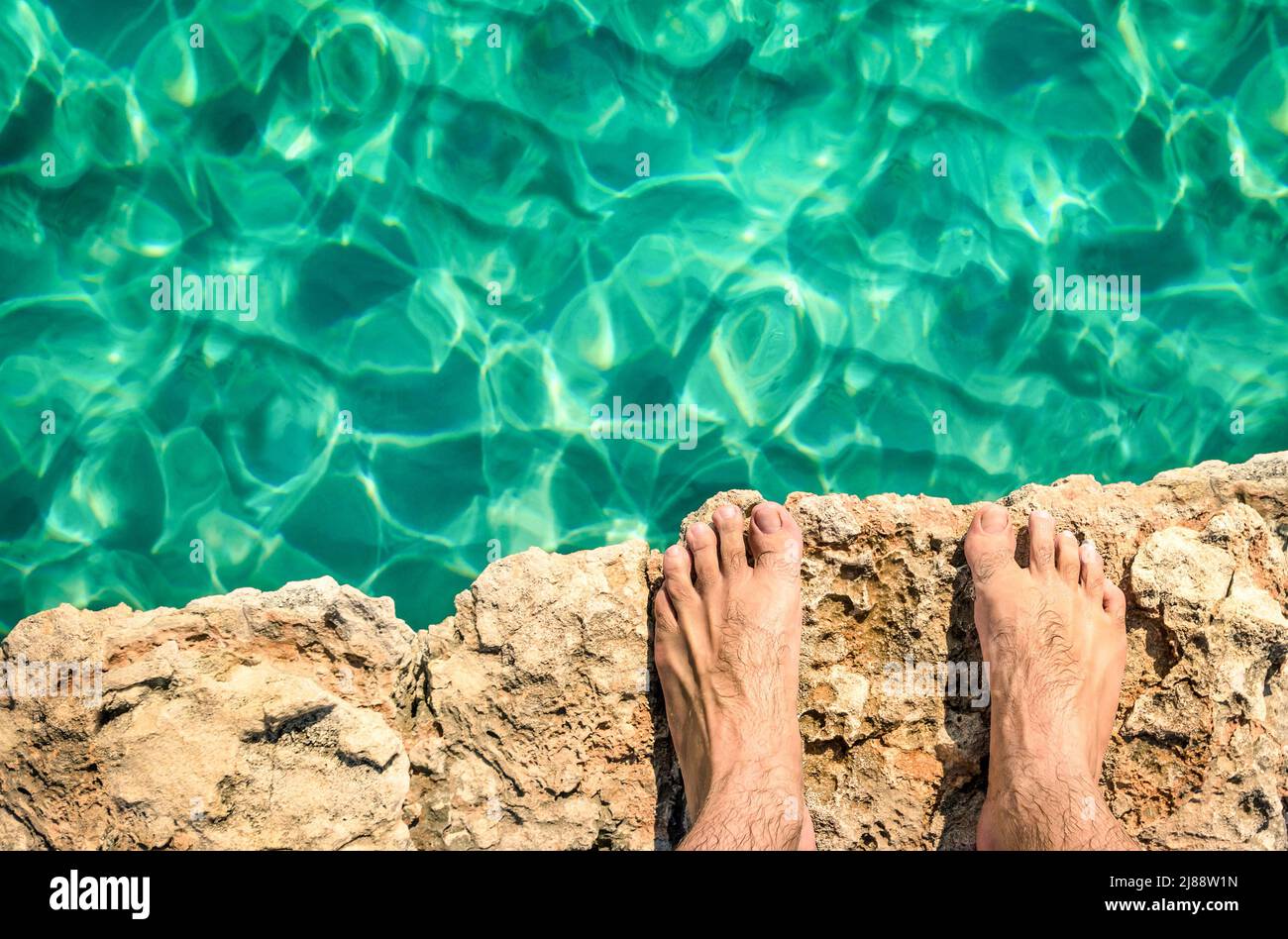 Humano desnudo descalzo en acantilado de roca listo para saltar en el agua azul claro - Comino y Gozo laguna azul en Malta - Libertad y estilo de vida sin preocupaciones durin Foto de stock