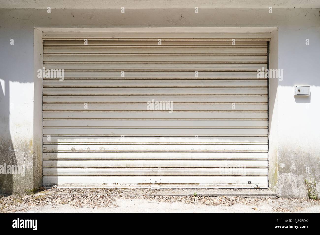 Fachada de un garaje sin limpiar con puertas grises Foto de stock