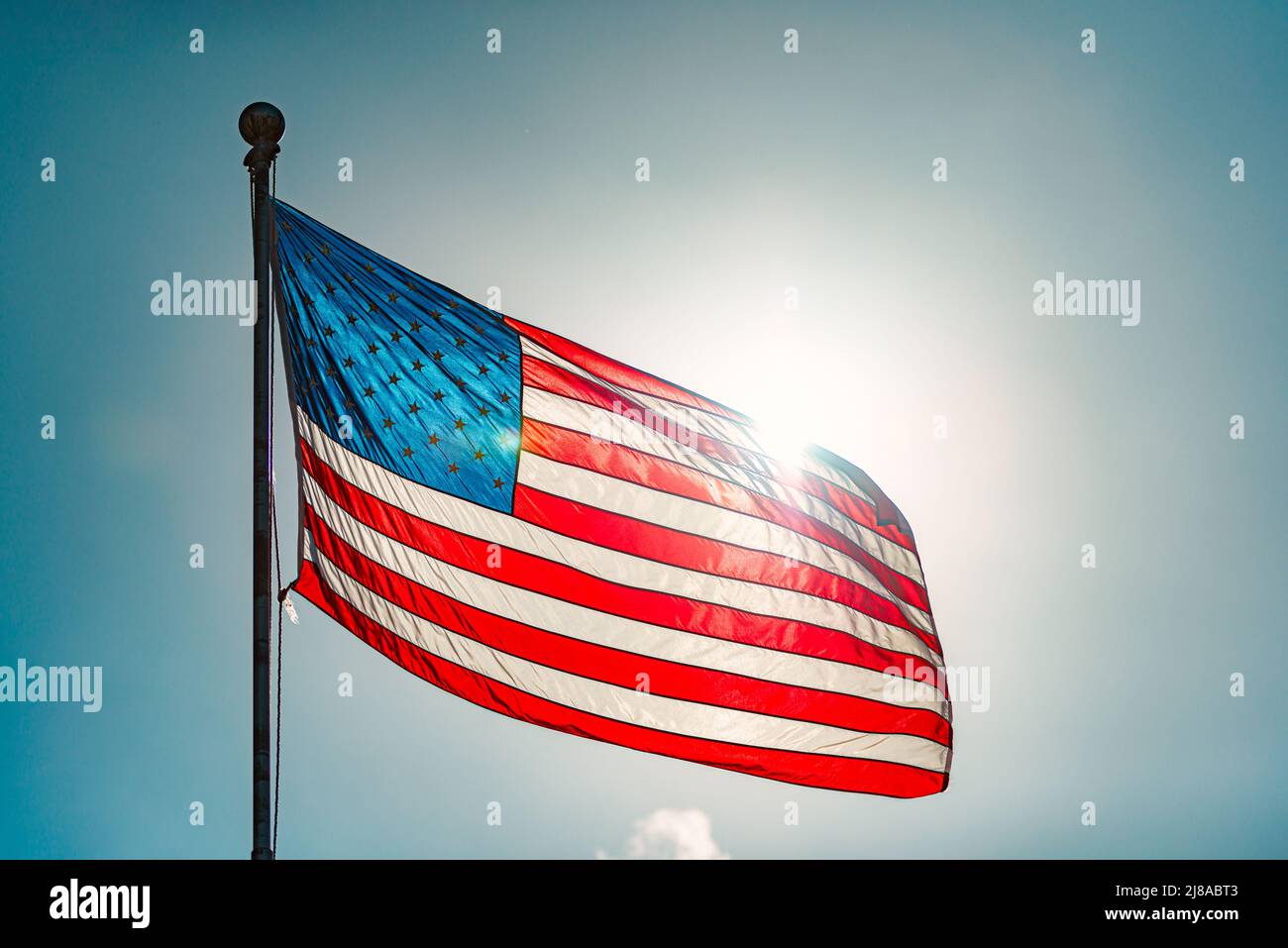 Bandera estadounidense y cielo azul nublado con nubes en el fondo Foto de stock