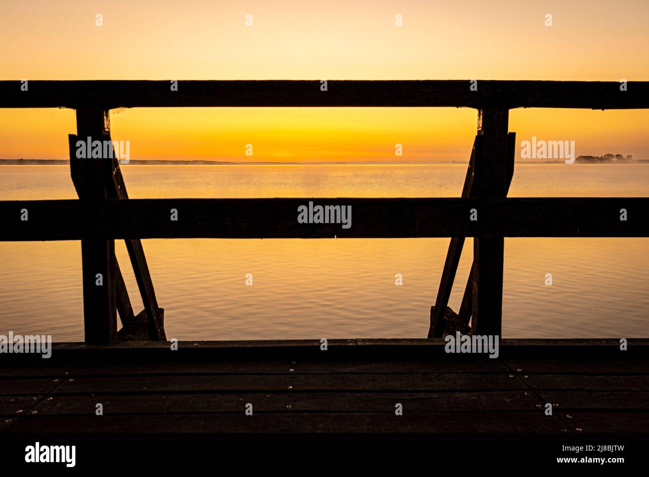 15 de mayo de 2022, Baja Sajonia, Winzlar: El cielo sobre un mirador en el Steinhuder Meer brilla amarillo poco antes del amanecer. Foto: Moritz Frankenberg/dpa Foto de stock