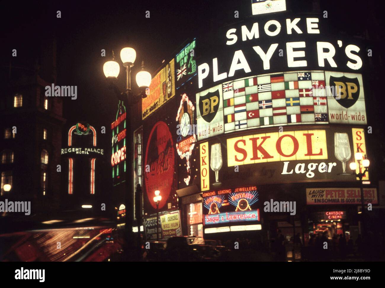Piccadilly Circus por la noche en 1957 Nota la publicidad de cigarrillos y la película de Peter Sellers Insomnia anuncios/ Foto de Tony Henshaw Archivo Foto de stock