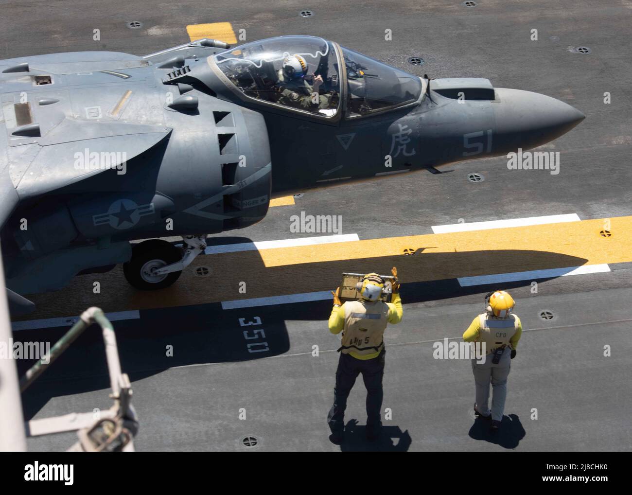 Los marineros de la Marina de los Estados Unidos preparan un arriero del Cuerpo de Infantería de Marina AV-8B adjunto al Escuadrón 542 de Tigers of Marine Attack, para lanzarse desde la cubierta de vuelo del buque anfibio de asalto USS Bataan, de clase Wasp, el 18 de junio de 2020 en el Mar Mediterráneo. Foto de stock