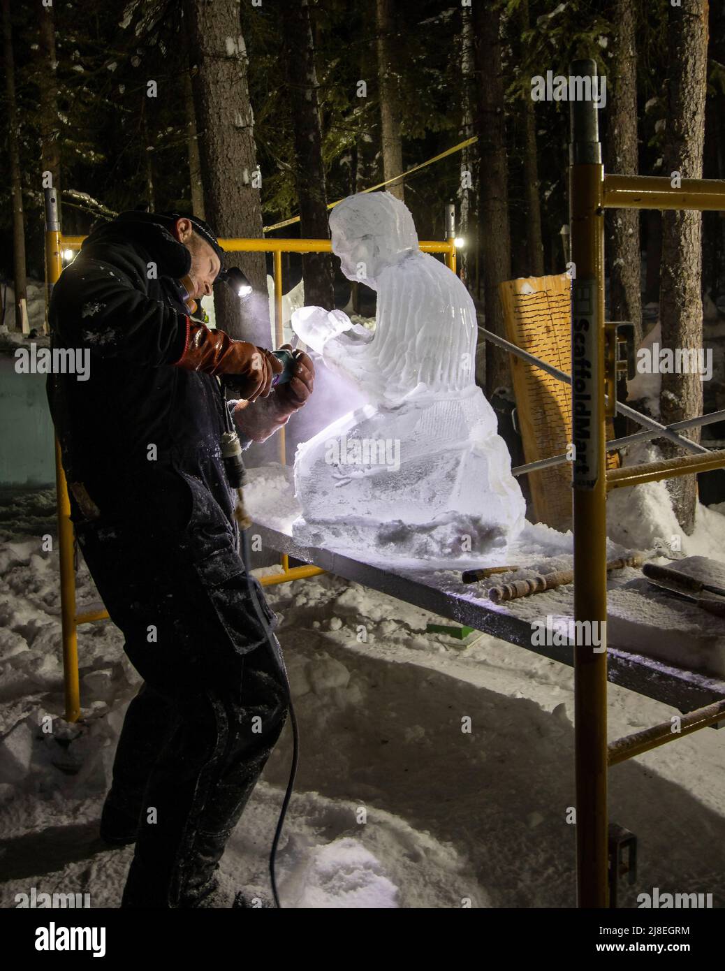 El hombre esculpe hielo en uno de los muchos carrvngs de hielo vistos en el Campeonato Mundial de Arte de Hielo fuera de Fairbanks, AK, en febrero. Foto de stock