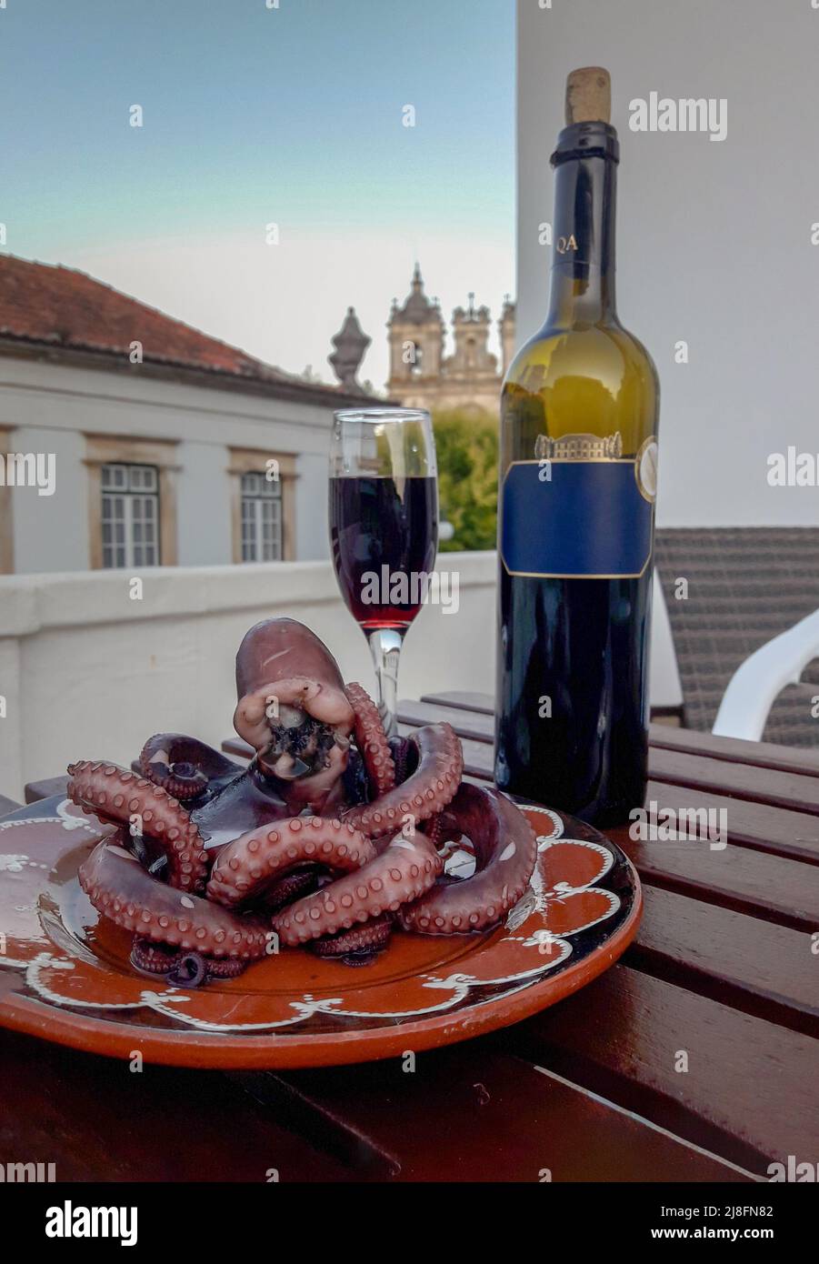 Botella con vaso de vino tinto y el pulpo desde el balcón del hotel Foto de stock