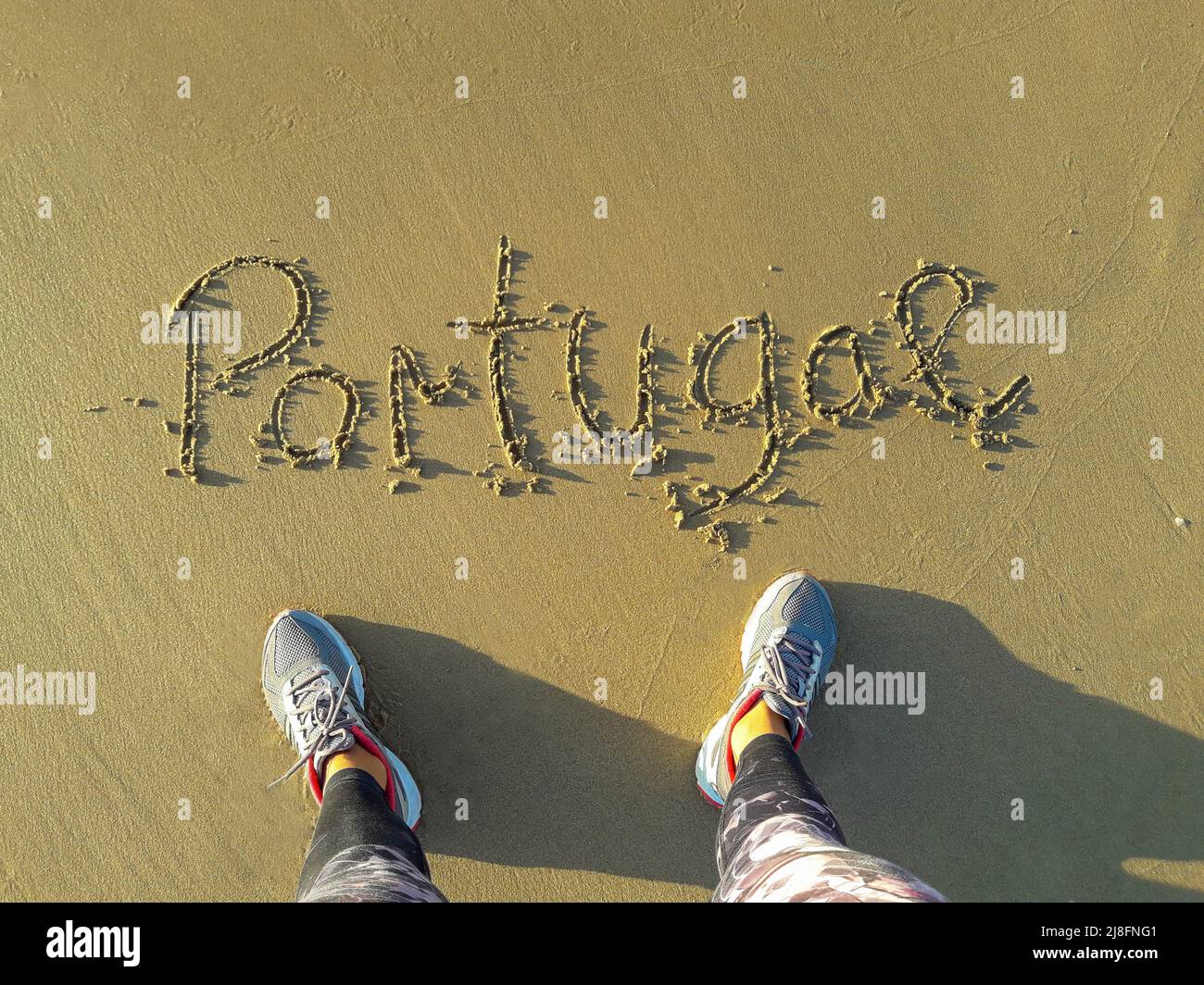 Portugal en la arena texto escrito a mano. pies desde arriba en una playa Foto de stock