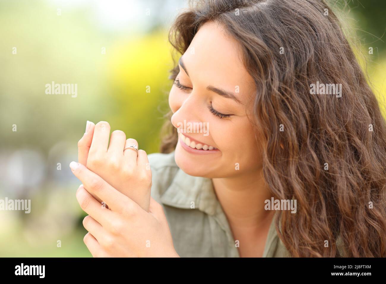 Mujer feliz mirando el anillo de bodas después de participar en un parque Foto de stock