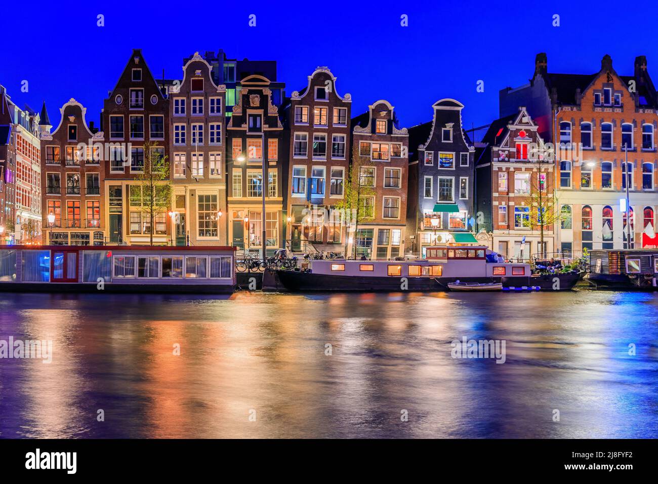 Ámsterdam, Países Bajos. Coloridas casas de baile en el canal Damrak. Foto de stock