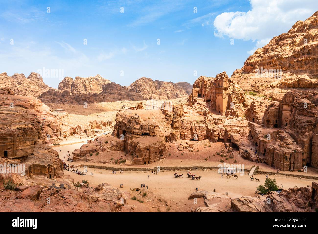 Vista a las antiguas tumbas reales de Nabataean y la calle principal de Petra llena de turistas, Jordania Foto de stock