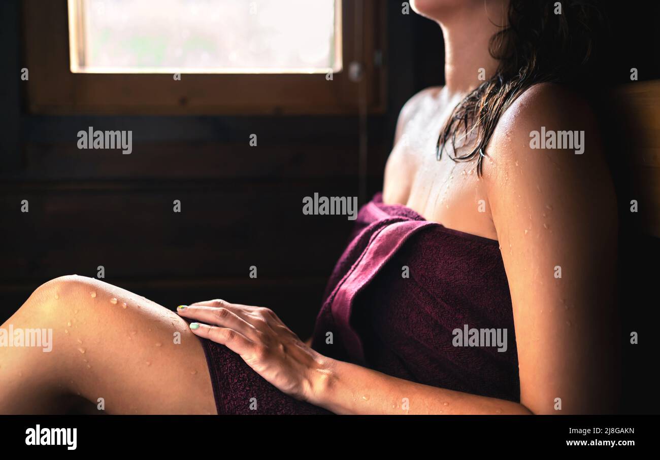 Mujer en la sauna. Sudor en la piel, toalla en el cuerpo y cabello mojado. Baño de vapor en el spa relajante de Finlandia en verano. Estilo de vida finlandés tradicional. Foto de stock