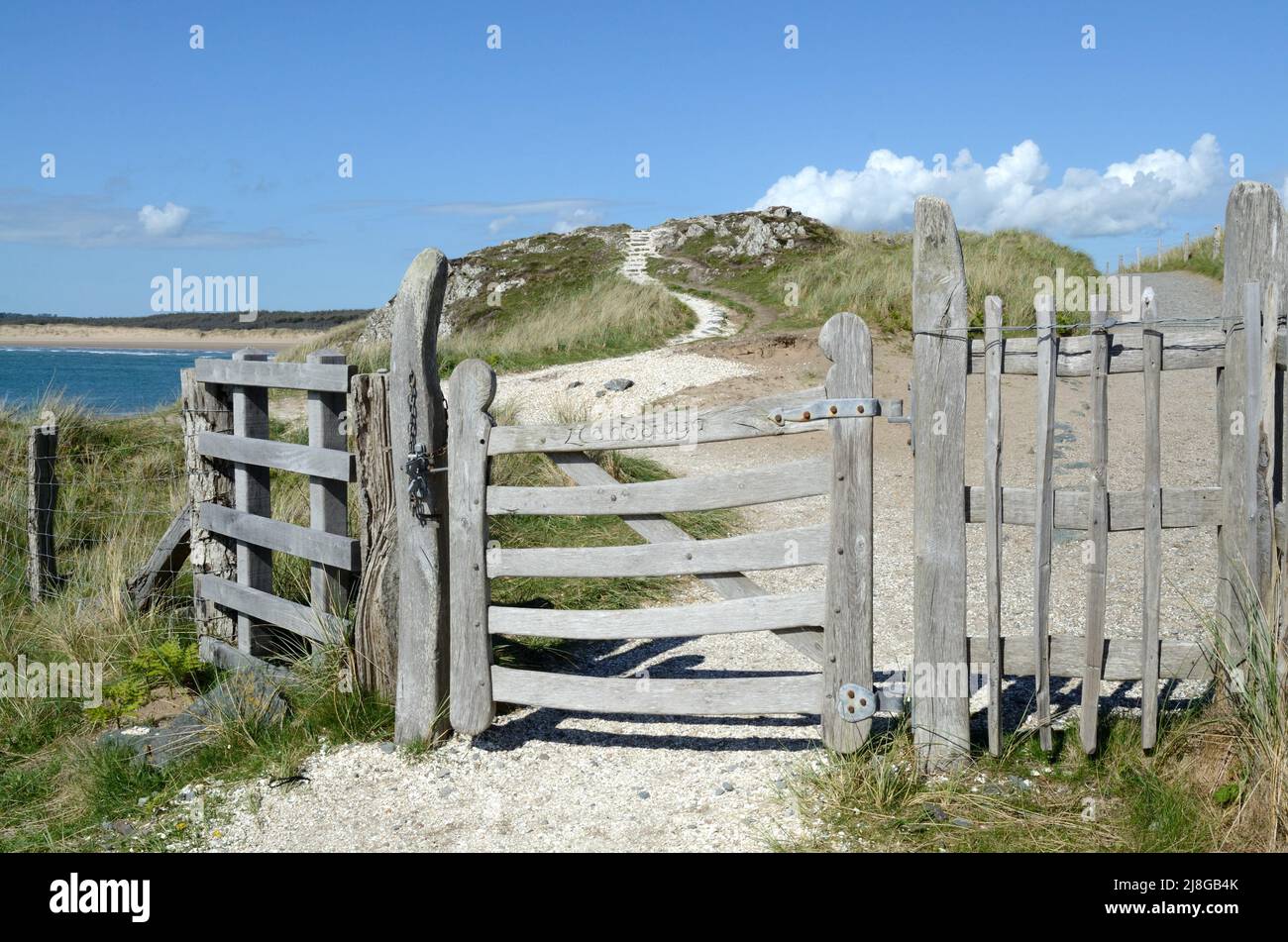 Puerta de madera inscrita y camino de concha de berberberechos Ynys Llanddwyn Isla anglesey Gales Cymru Reino Unido Foto de stock