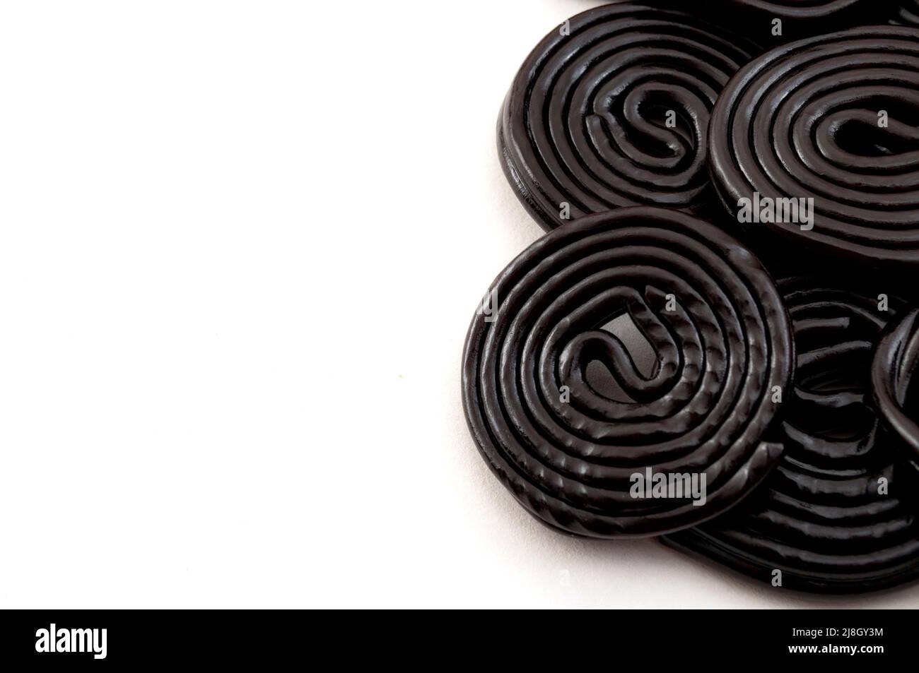 Espirales de regaliz negro, dulces masticables y delicioso concepto de postre con ruedas de regaliz que se saborean con el extracto de la raíz del Glycyr Foto de stock