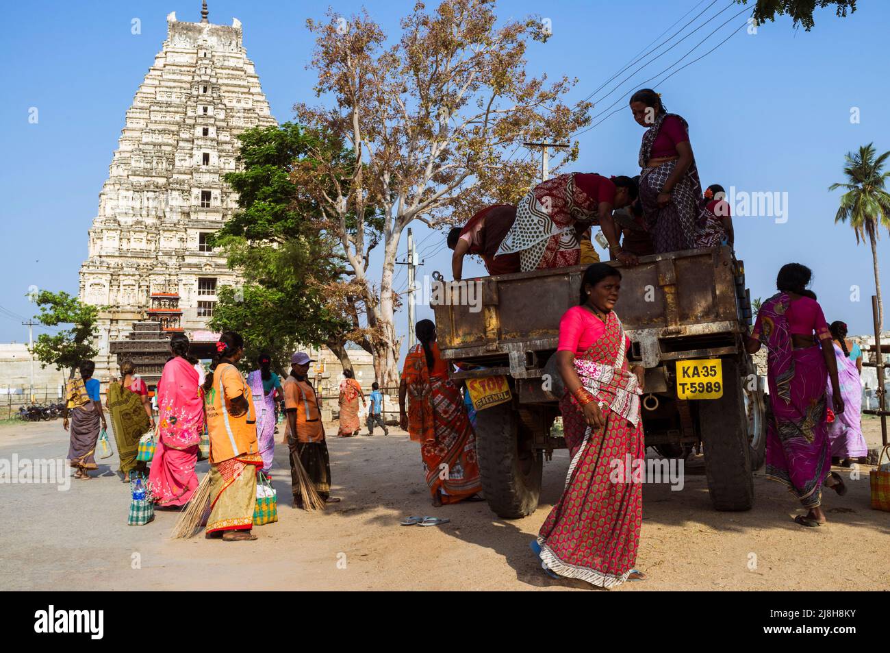 Hampi, Karnataka, India: Un colorido grupo de mujeres se junta con un camión frente al Templo de Sree Virupaksha. Se cree que funciona ininterrumpidamente Foto de stock