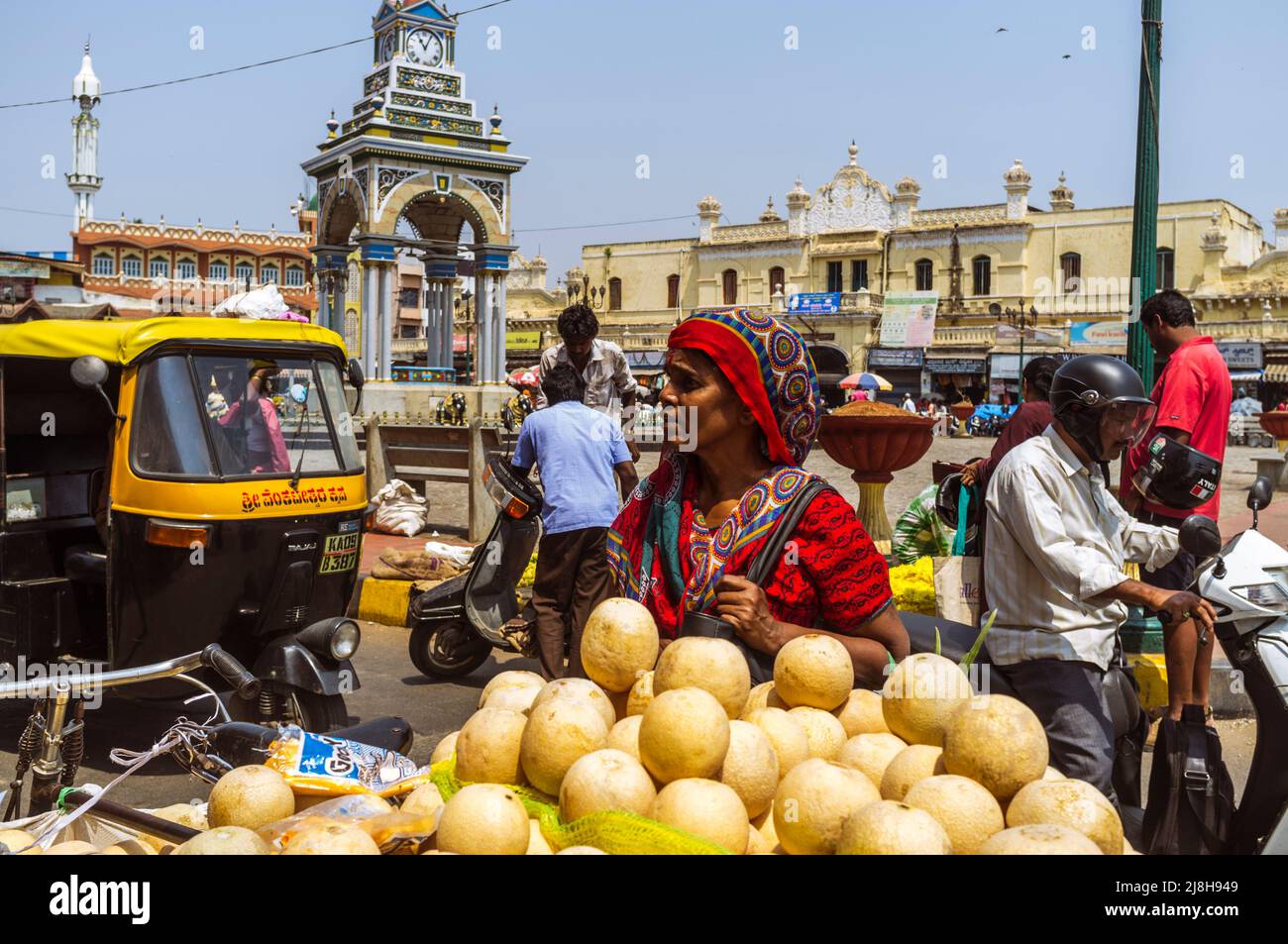 Mysore, Karnataka, India : Una mujer compra fruta en un puesto al lado de la Torre del Reloj Dufferin fuera del mercado Devaraja. Foto de stock