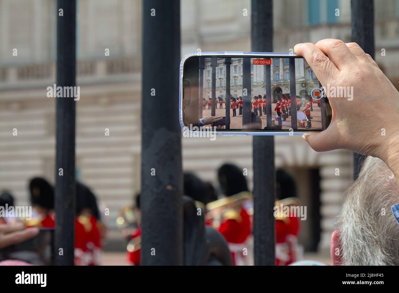 Persona que vídee con un teléfono móvil La Banda Regimental de los Guardias de Granadero durante la Ceremonia de Cambio de Guardia en el Palacio de Buckingham de Londres Foto de stock