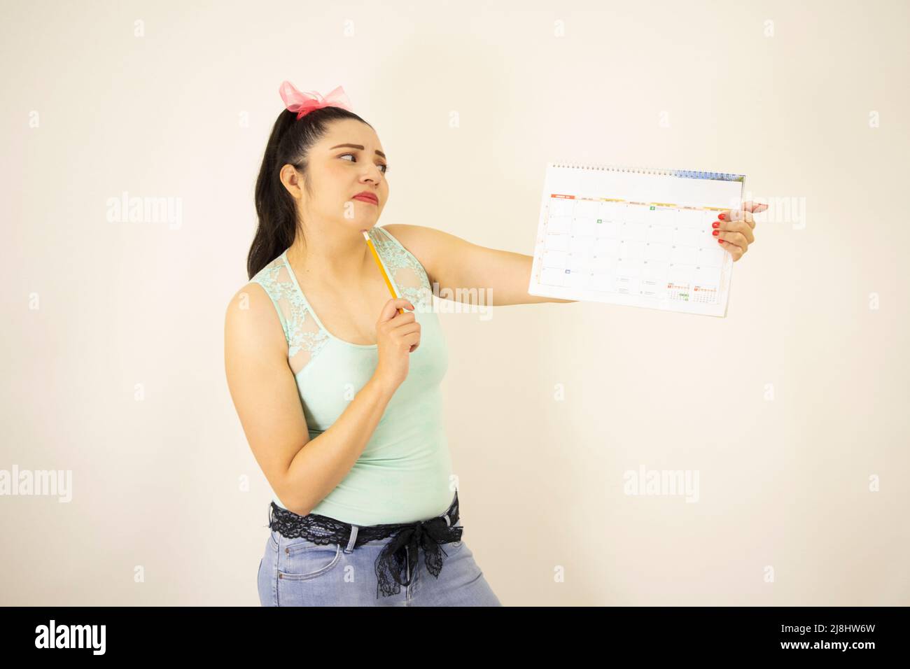 joven hermosa estudiante de pie apuntando a un calendario Foto de stock