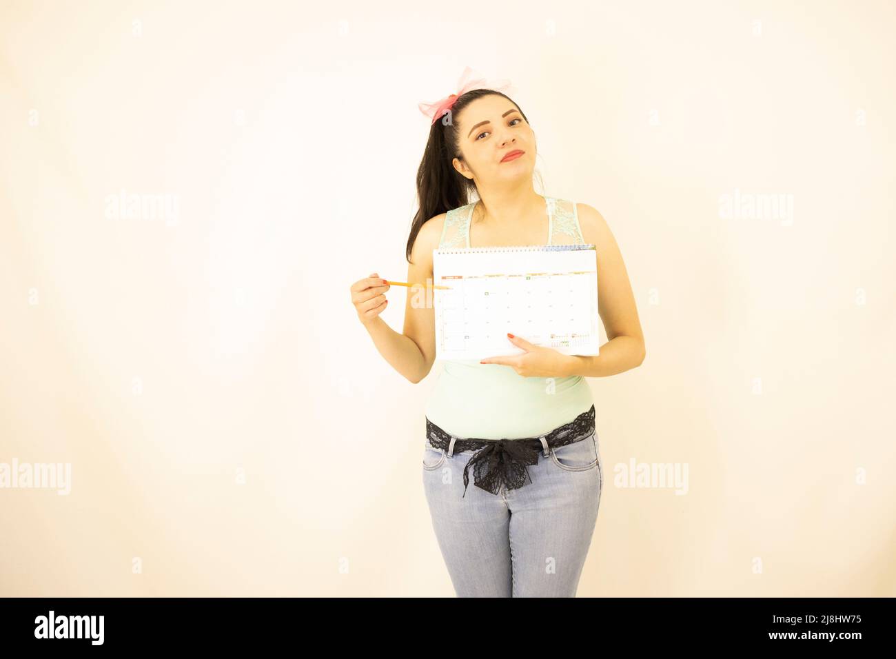 joven hermosa estudiante de pie apuntando a un calendario Foto de stock