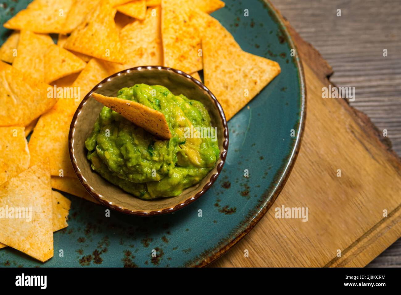 Plato de nachos con salsa guacamole. Utensilios hechos a mano. Riego bucal. Comida de fiesta. Foto de stock