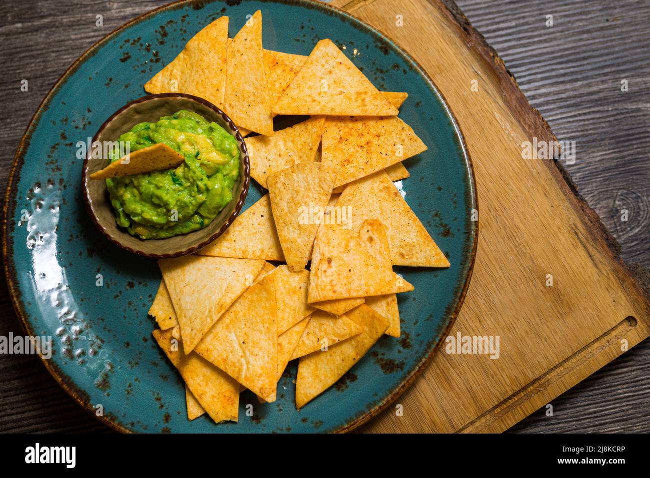 Plato de nachos con salsa guacamole. Utensilios hechos a mano. Riego bucal. Comida de fiesta. Foto de stock