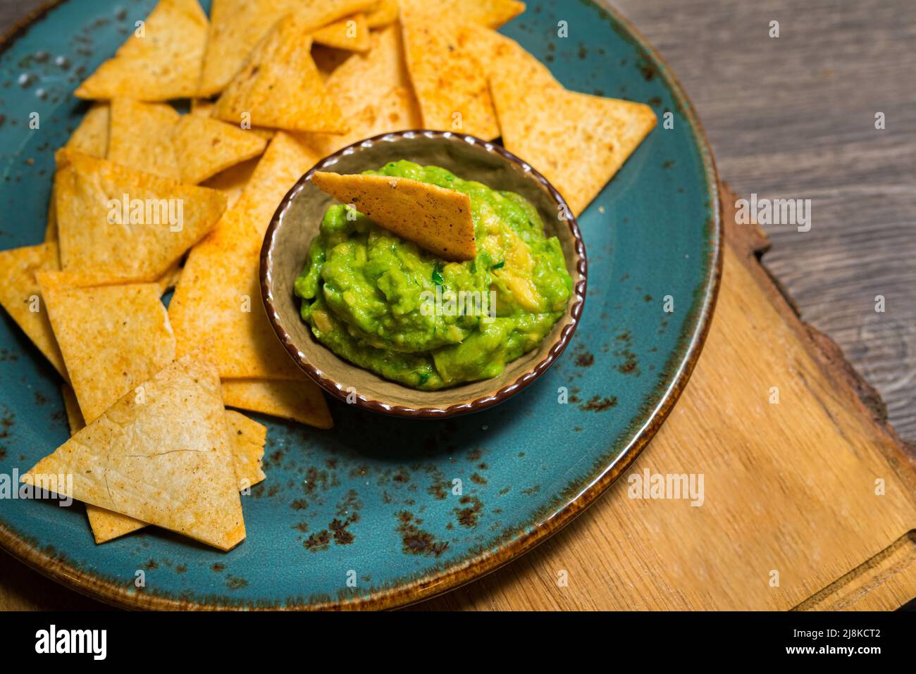 Plato de nachos con salsa guacamole. Utensilios hechos a mano. Riego bucal. Comida de fiesta. Foto de stock