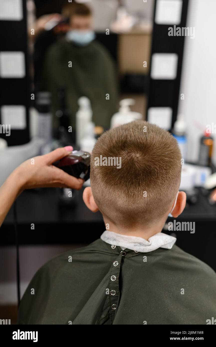 niño pequeño en una máscara, que se corta en la barbershop en la  barbershop, corte de pelo de moda y con estilo para un niño, máquina de  escribir corte de pelo Fotografía
