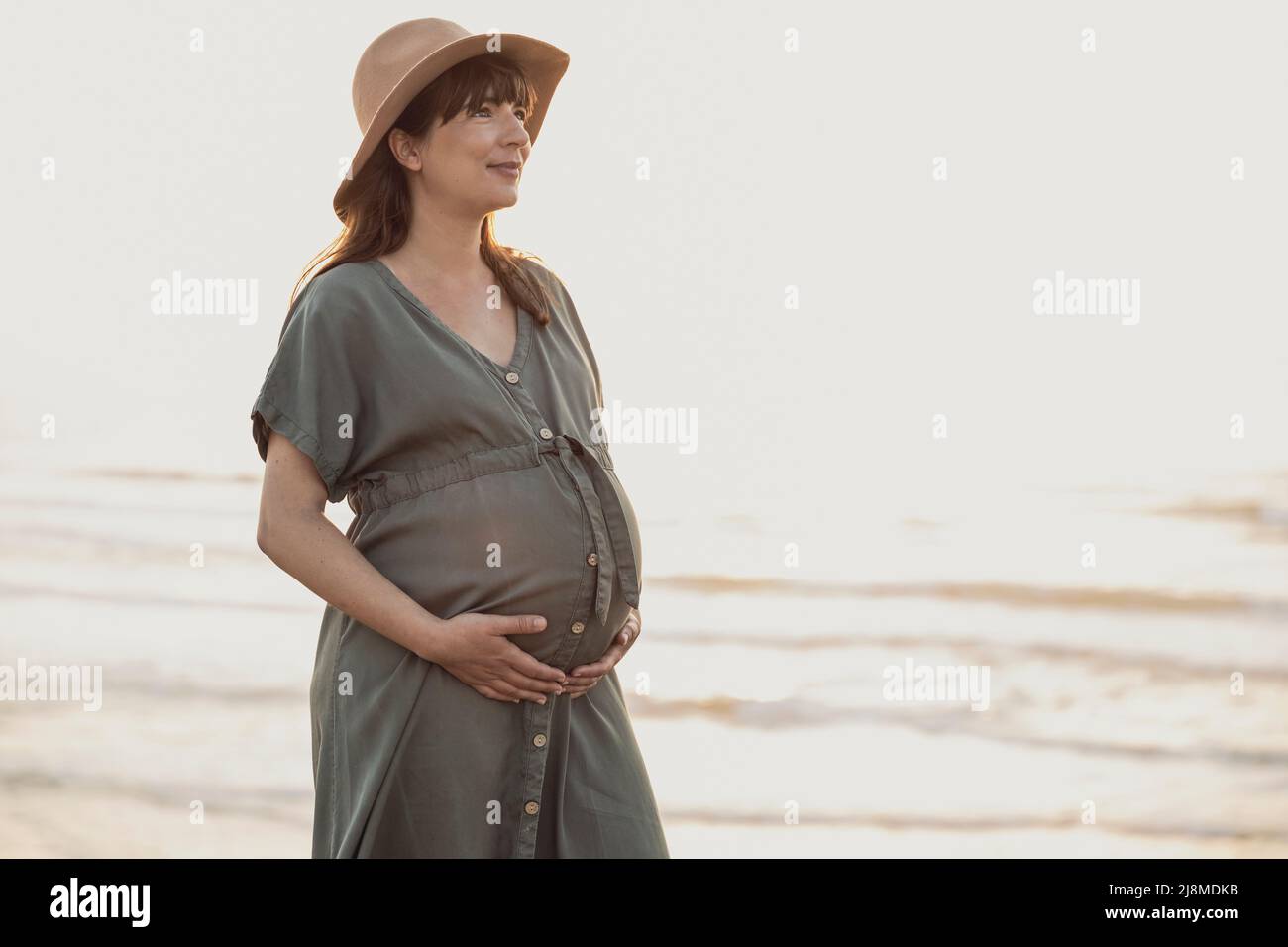 Mujer embarazada en la playa al atardecer disfrutando de la vista Foto de stock
