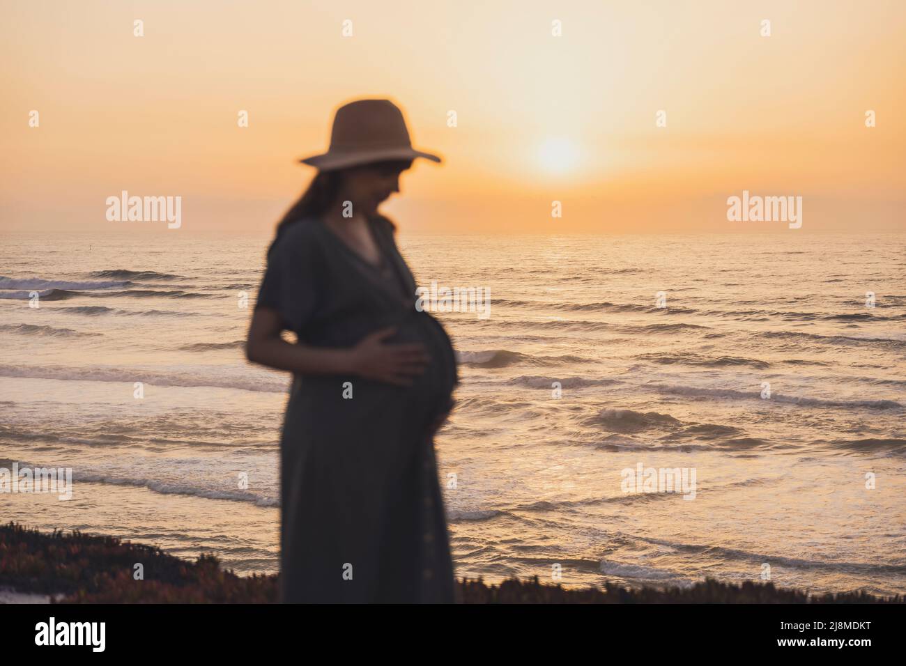 Mujer embarazada en la playa al atardecer disfrutando de la vista Foto de stock