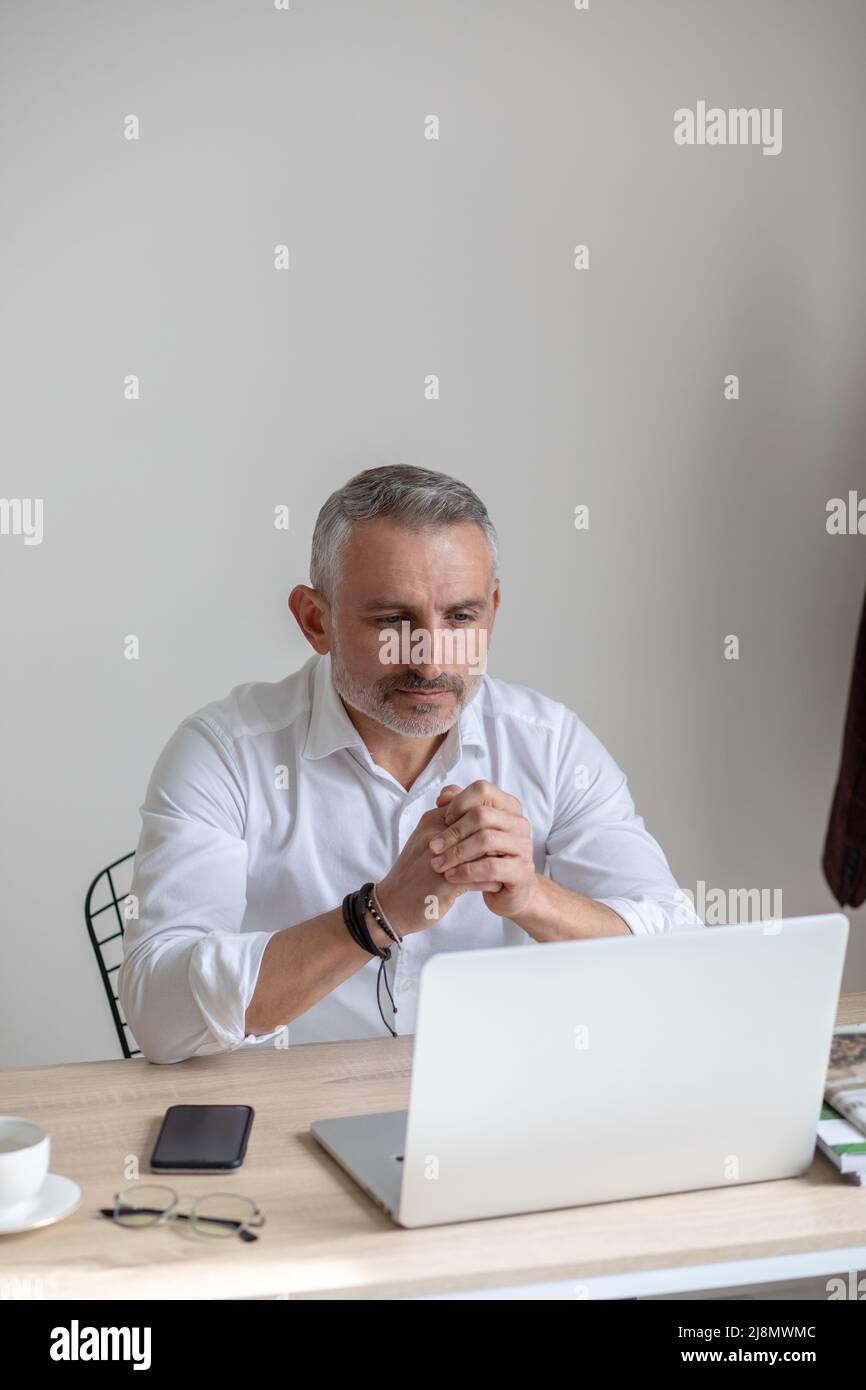 Un hombre de negocios atento mirando al ordenador portátil sentado en la mesa Foto de stock
