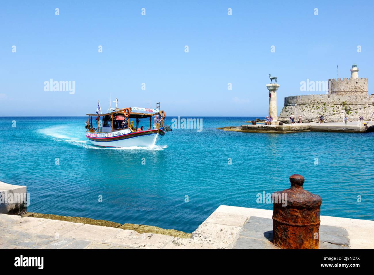 Un grupo de turistas, en un viaje de turismo, a bordo de un pequeño barco que regresa al puerto de Mandhraki en la histórica ciudad de Rodas, Rodas, Grecia Foto de stock