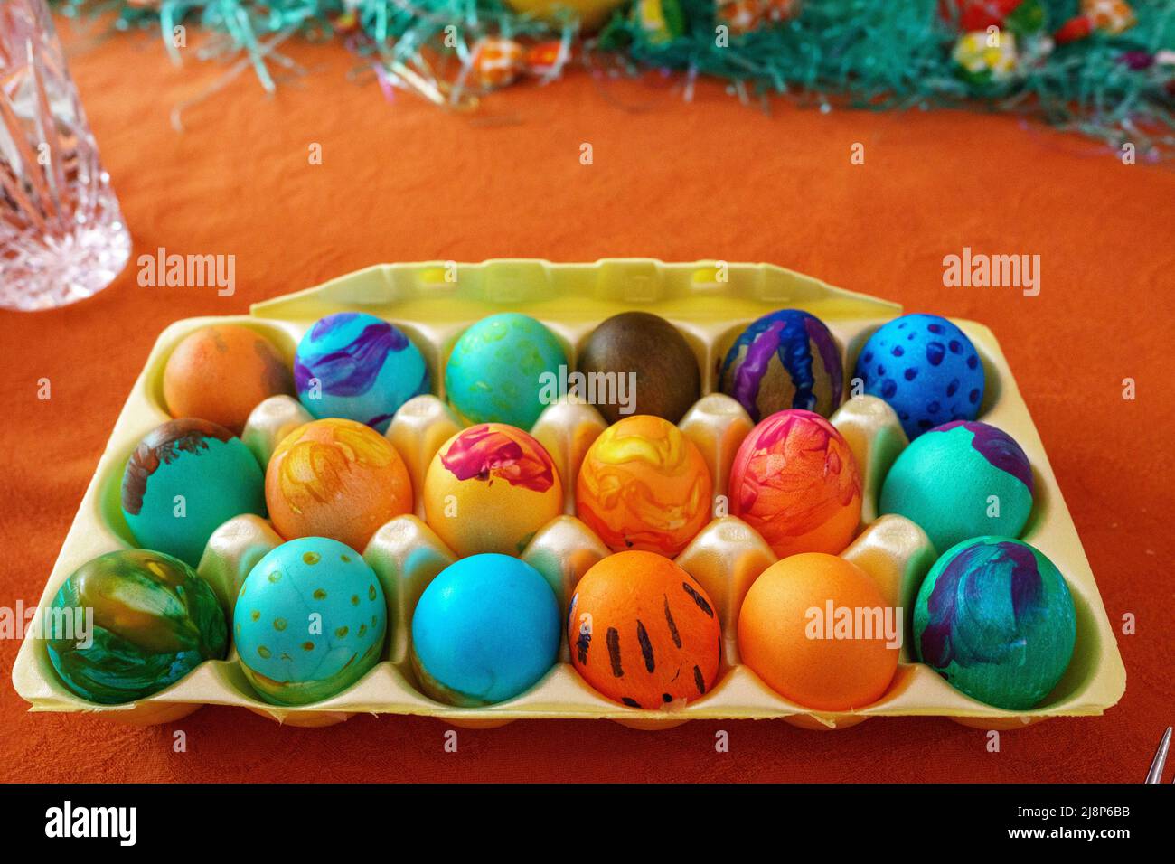 Cartón de huevos de Pascua teñidos en casa sobre manteles de naranja Foto de stock