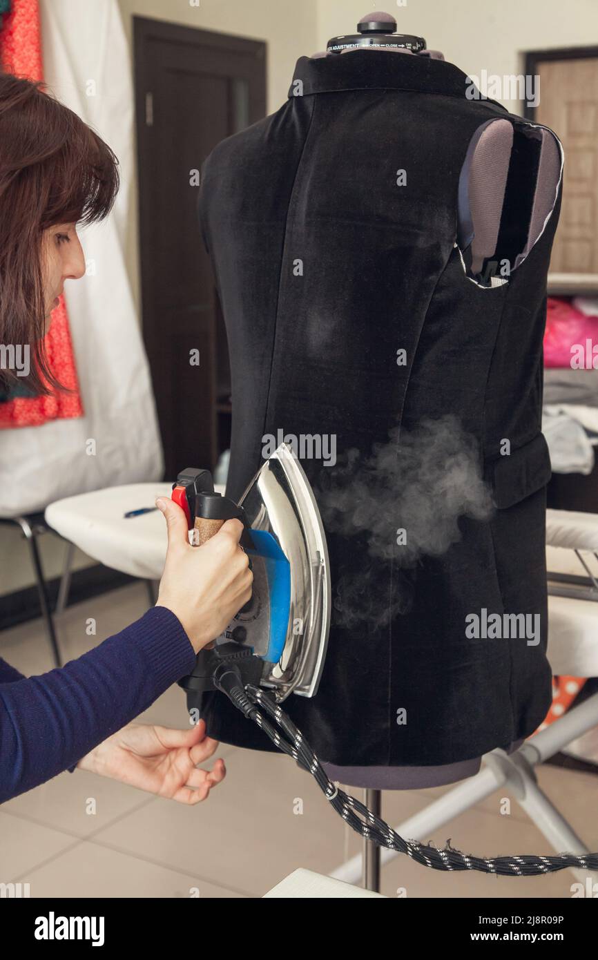 Una mujer costurera plancha una chaqueta inacabada sobre un maniquí  Fotografía de stock - Alamy
