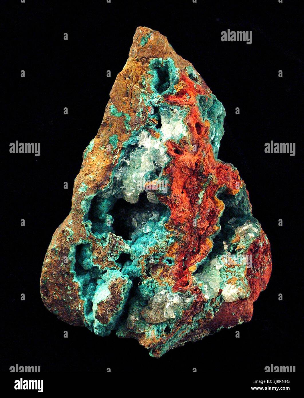 Malaquita Esta muestra de 10 cm de altura, de un lugar desconocido, contiene una notable malaquita azul turquesa, Cu2(CO3)(OH)2, con limonita marrón-amarilla y marrón-roja (una mezcla oxidada de diversos hidróxidos y óxidos de hierro). Cristales claros de calcita, CaCO3, han crecido en algunos de los espacios abiertos. Malaquita es un mineral bonito, y algunos especímenes son piedras preciosas semi-preciosas. A menudo se precipita en varras formando capas de diferentes colores, como en esta fotografía. Los cristales individuales son raros. Malaquita se encuentra comúnmente con otros minerales hermosos, incluyendo azurita y chrysocolla. Foto de stock