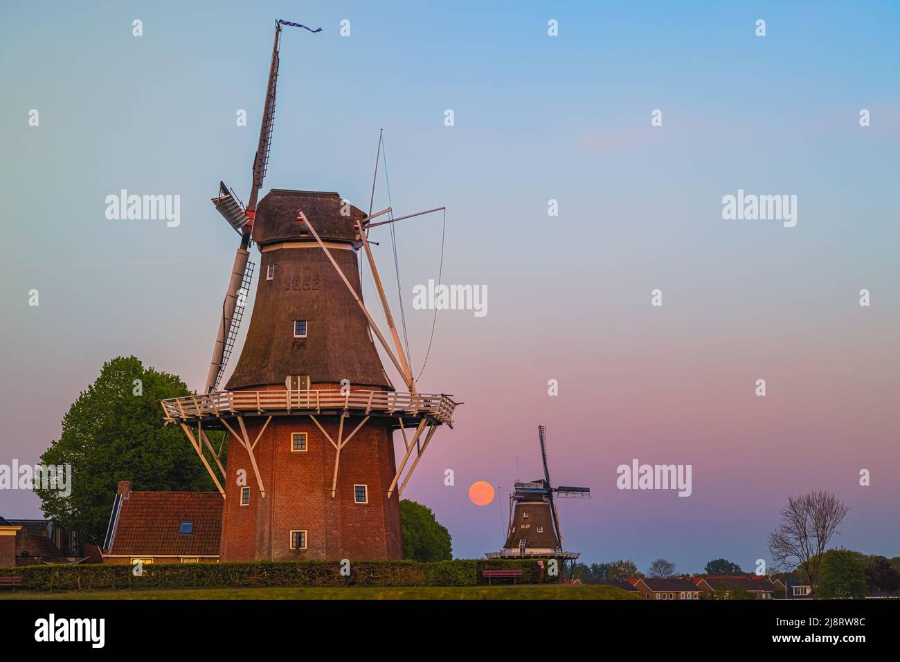 Puesta de sol y puesta de luna llena cerca de Flour Mill 'De Hoop' y 'Zeldenrust' en la ciudad holandesa de Dokkum, en la provincia de Frisia en el norte Foto de stock