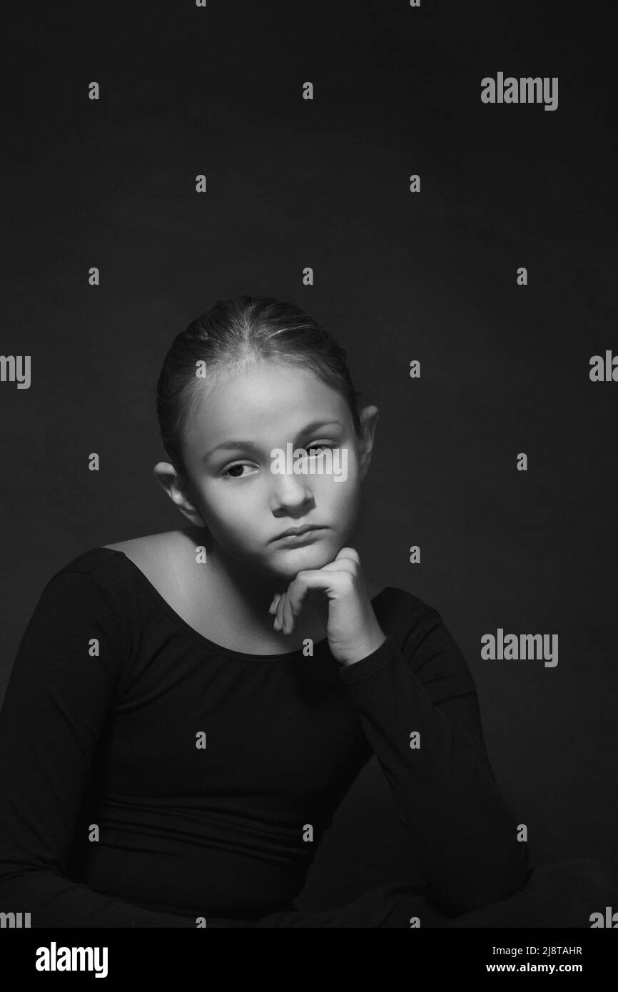 Chica con triste expresión facial en blanco y negro, cabeza apoyada en la mano Foto de stock