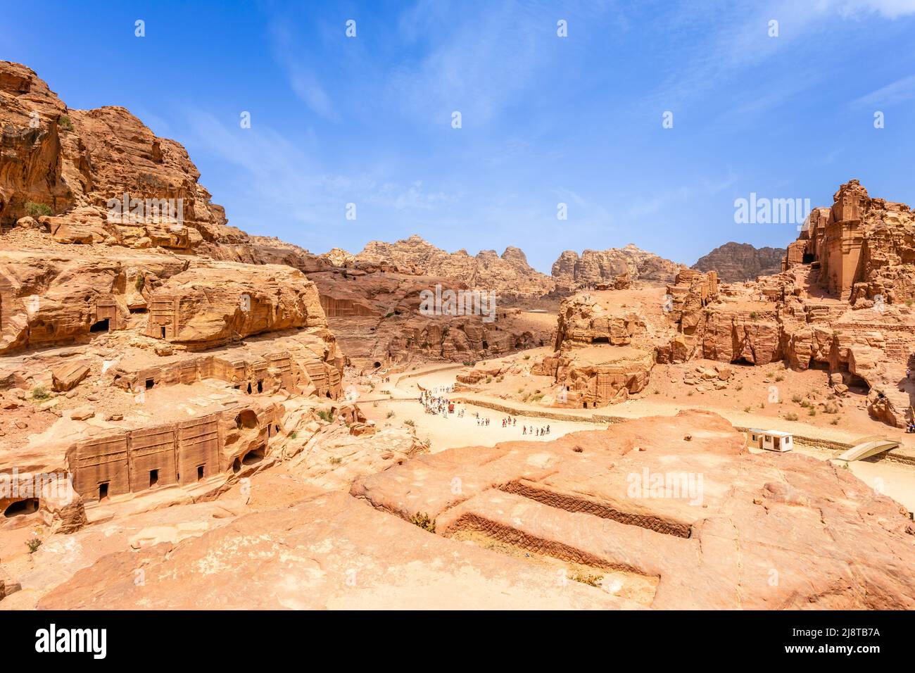 Vista a las antiguas tumbas reales de Nabataean y la calle principal de Petra llena de turistas, Jordania Foto de stock