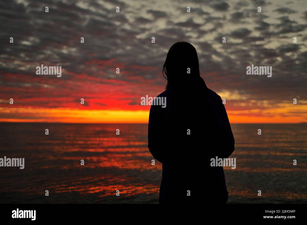 Una joven adolescente mira con asombro, maravilla y admiración a un magnífico Sunset Sky Foto de stock