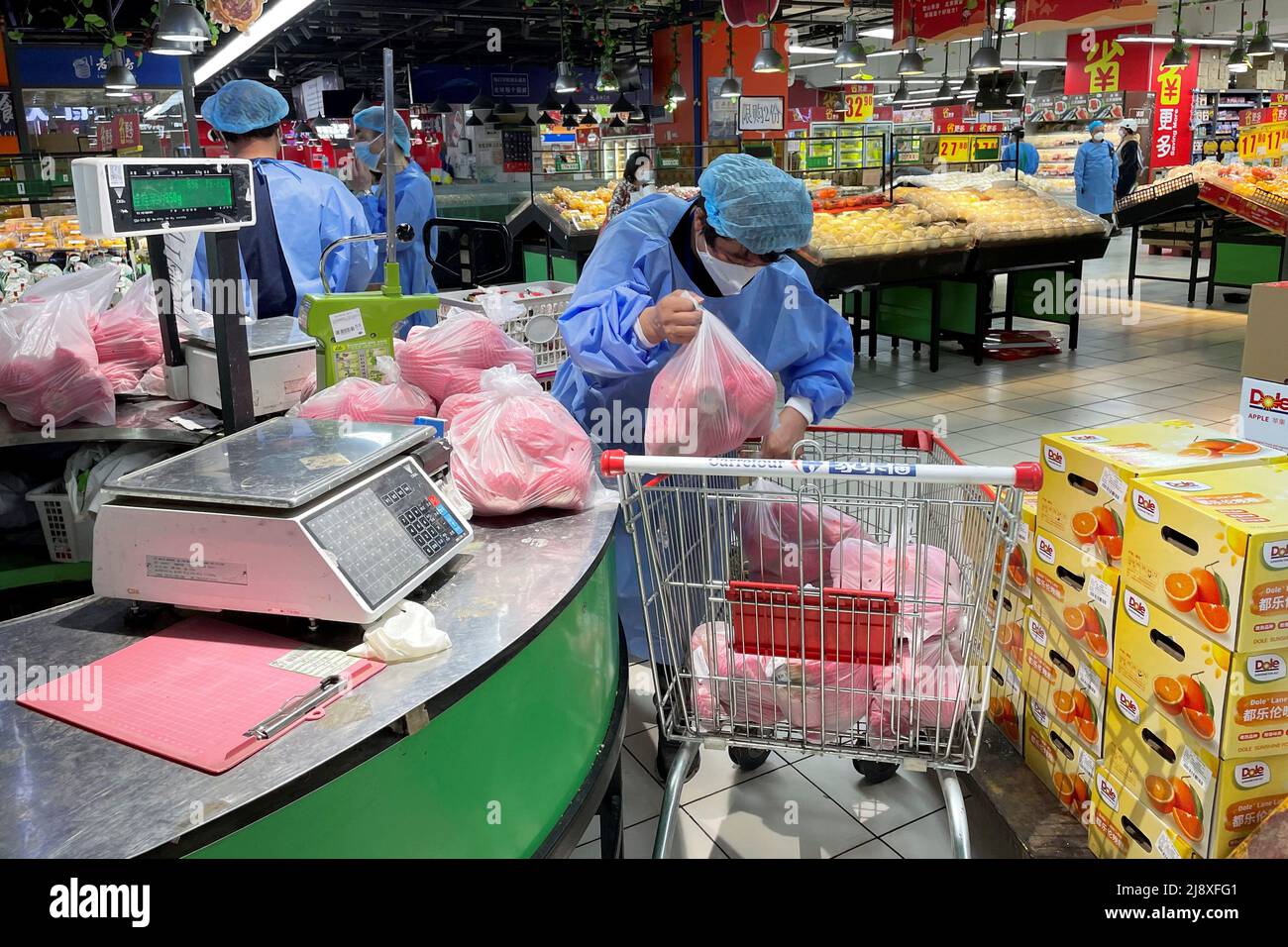 Un trabajador en traje protector clasifica las verduras en un carro de la compra, en supermercado Carrefour reabierto en medio del brote de la enfermedad de coronavirus (COVID-19) en Shanghai, China,
