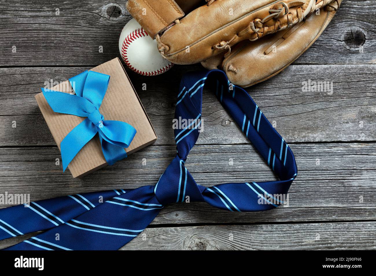 Concepto de vacaciones para el Día de los Padres en madera rústica con guante de béisbol, corbata y caja de regalo Foto de stock