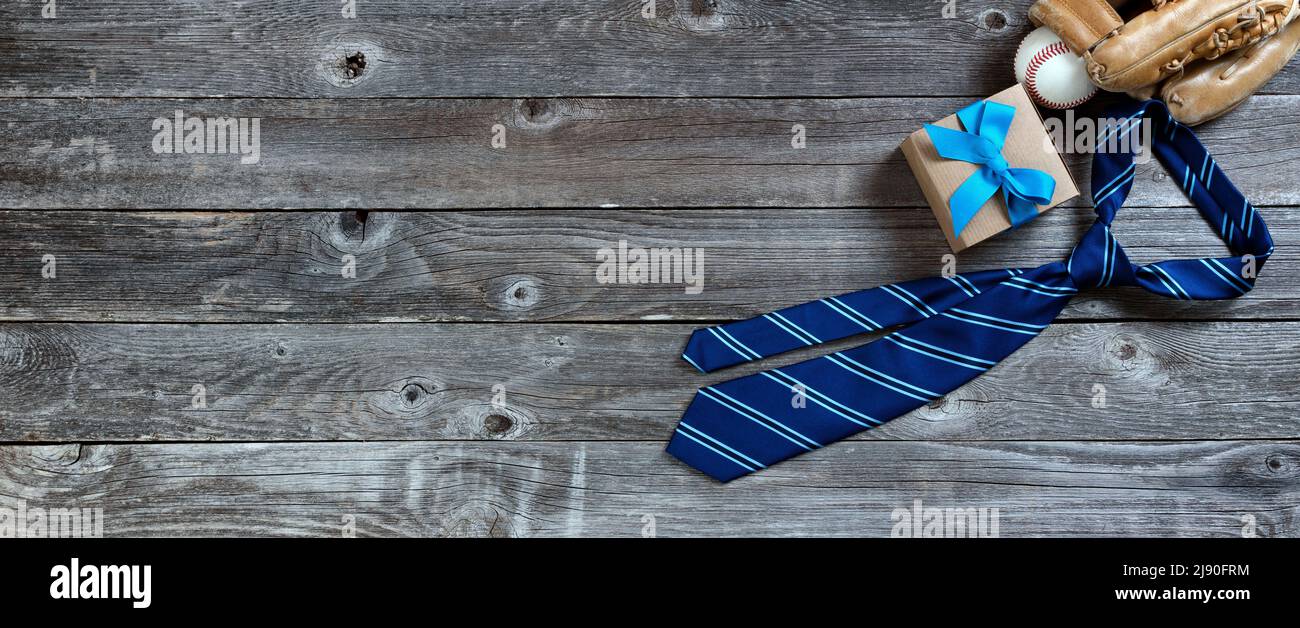 Corbata de vestido de rayas azules, regalo y guante de béisbol con bola para el concepto de vacaciones del Día de los Padres en madera rústica Foto de stock