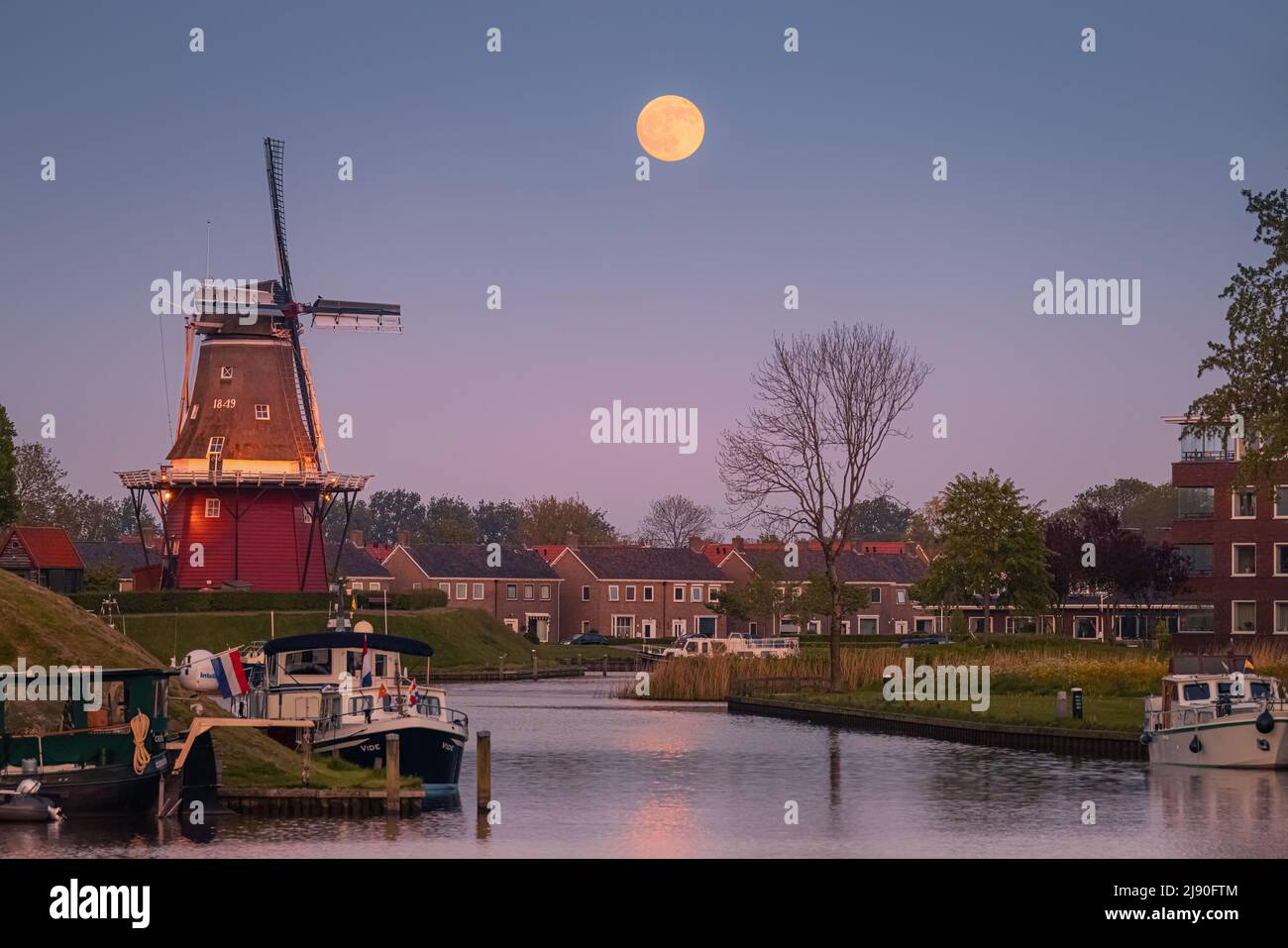 Puesta de sol y puesta de luna llena cerca de Flour Mill 'De Hoop' en la ciudad holandesa de Dokkum, en la provincia de Frisia en la parte norte de la N Foto de stock