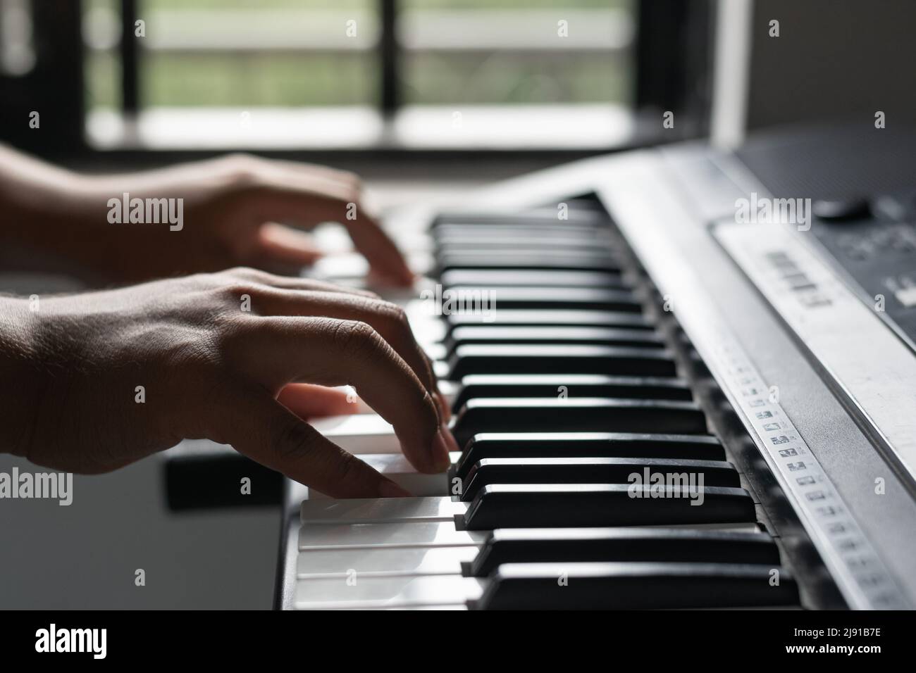 joven latino que crea una canción en un sintetizador. detalle de las manos  de un músico tocando piano. aficiones en casa a la luz natural. concierto  musical Fotografía de stock - Alamy