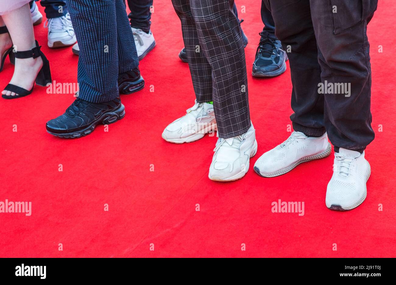 Pies de invitados de baile de pie sobre una alfombra roja, foto de cerca Foto de stock