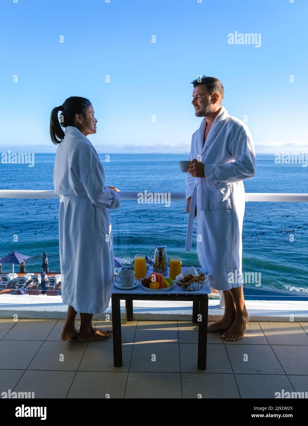 Cape Town Sudáfrica hombre pareja y mujeres bebiendo café durante el  amanecer en el balcón en vacaciones en Ciudad del Cabo Sudáfrica. Hombres  europeos y mujeres asiáticas despertando con café mirando al