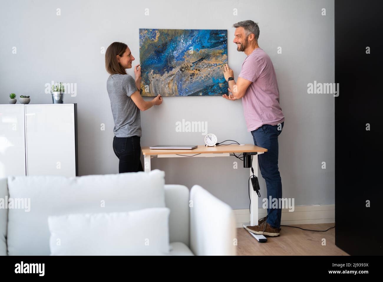 Feliz pareja de colgar la pintura. Decoración de la pared en casa Foto de stock