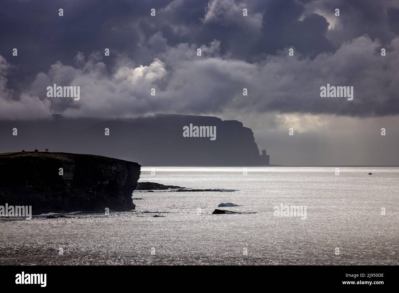 Dos figuras en los acantilados de Yesnaby con Hoy Beyond, Islas Orkney, Escocia, Reino Unido Foto de stock