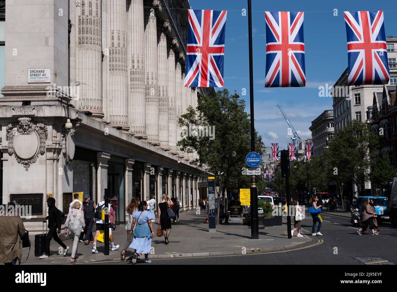 Union Flags colgando en lo alto de Oxford Street mientras los compradores, visitantes y londinenses pasan por la celebración de la Reina Elizabeth IIS próximo Jubileo Platino el 17th de mayo de 2022 en Londres, Reino Unido. En 2022, Su Majestad la Reina Isabel II se convertirá en el primer monarca británico en celebrar un jubileo de platino con motivo del 70th aniversario de su adhesión al trono el 6 de febrero de 1952. Oxford Street es un importante centro comercial en el extremo oeste de la capital y es la calle comercial más concurrida de Europa, con alrededor de medio millón de visitantes diarios a sus aproximadamente 300 tiendas, la mayoría de las cuales lo son Foto de stock