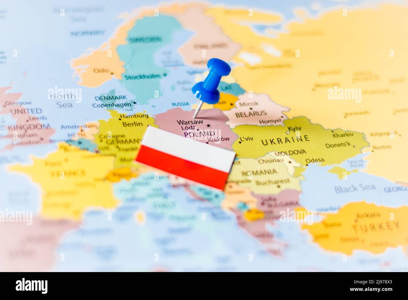 Alfiler azul que apunta a Polonia junto con una bandera polaca en un mapa político del mundo Foto de stock