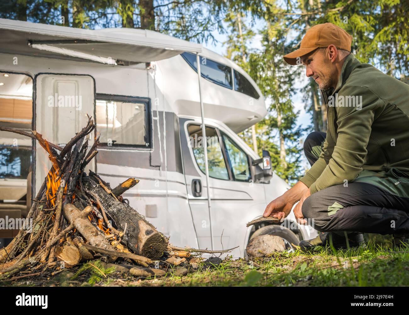 Viaje por carretera de verano y tema de Van Life. Hombres Caucásicos Colgándose cerca de Campfire y acampar en un vehículo recreativo Camper Van RV. Foto de stock